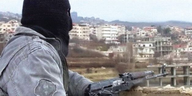 EDITOR'S NOTE: REUTERS CANNOT INDEPENDENTLY VERIFY CONTENT OF VIDEO FROM WHICH THIS STILL IMAGE WAS TAKEN.A member of the Free Syria Army with an assault rifle stands guard during a patrol in the western border town of Zabadani in this undated still image taken from amateur video obtained by Reuters January 16, 2012. Masked gunmen prowl the rain-swept streets of the once-relaxed Syrian hill resort, which they have transformed into a hub of revolt against President Bashar al-Assad's rule. Zabadan