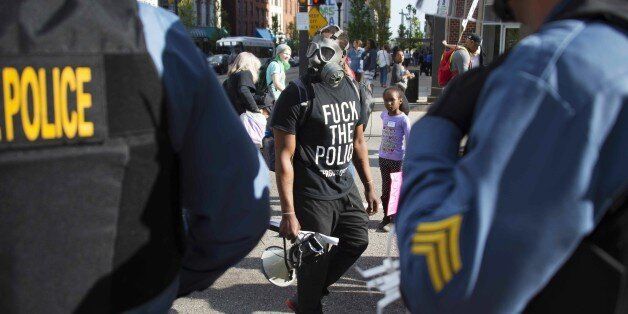 A demonstrator looks at police as he marches in Baltimore, Maryland, May 2, 2015. Thousands of people protested in Baltimore in fresh demonstrations, a day after six police officers were charged over the death of Freddie Gray. AFP PHOTO/JIM WATSON (Photo credit should read JIM WATSON/AFP/Getty Images)