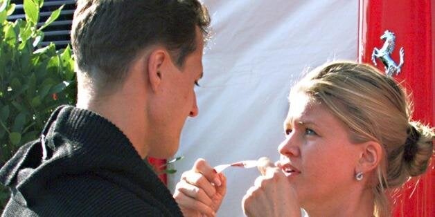 NURBURGRING, GERMANY: German Ferrari driver Michael Schumacher embraces his wife Corinna, 25 September after the first free practice session at the Nurburgring, two days before the Luxembourg Formula one Grand Prix. The couple announced last week they were expecting a second baby in seven months time. They already have a 19-month-old girl called Gina Maria. (ELECTRONIC IMAGE) (Photo credit should read PIERRE VERDY/AFP/Getty Images)