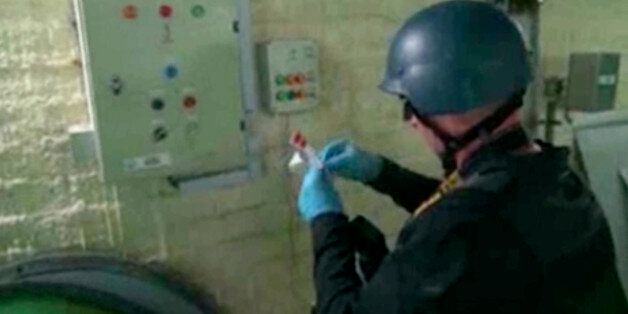 This image made from video broadcast on Syrian State Television on Tuesday, Oct. 8, 2013 purports to show a chemical weapons expert examining taking samples at a chemical weapons plant at an unknown location in Syria. The joint OPCW-U.N. mission to scrap Syria's chemical program stems from a deadly Aug. 21 attack on opposition-held suburbs of Damascus in which the U.N. has determined the nerve agent sarin was used. Hundreds of people were killed, including many children. The U.S. and Western all