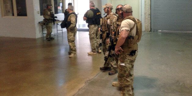 Members of the Garland Police Department are stand inside the Curtis Culwell Center on Sunday, May 3, 2015, in Garland, Texas. A contest for cartoons depictions of the Prophet Muhammad in the Dallas suburb is on lockdown Sunday after authorities reported a shooting outside the building. (AP Photo Nomaan Merchant)