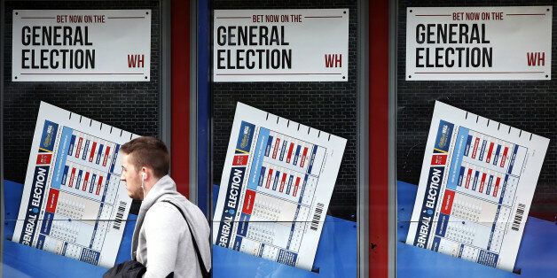 A member of the public walks past a betting shop window with a display for the General Election in Govan, Scotland, Wednesday, May 6, 2015. Britain goes to the polls in a General Election Thursday. (AP Photo/Scott Heppell)
