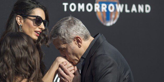 Actor George Clooney kisses the hand of Amal Clooney after arriving for the premiere of Disney's Tomorrowland in Anaheim, California on May 9, 2015. AFP PHOTO/ DAVID MCNEW (Photo credit should read DAVID MCNEW/AFP/Getty Images)