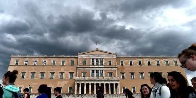People walk in front of the Greek Parliament in Athens on April 7, 2015. Greek lawmakers voted on April 7 to set up a committee to examine the circumstances under which Greece agreed to bailouts totaling 240 billion euros (USD 260 billion) with the European Union and International Monetary Fund. AFP PHOTO / ARIS MESSINIS (Photo credit should read ARIS MESSINIS/AFP/Getty Images)