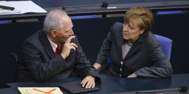 German Finance Minister Wolfgang Schaeuble (L) speaks with German Chancellor Angela Merkel before presenting his draft budget for 2014 to lawmakers during a plenary session at the lower house of parliament Bundestag on April 8, 2014 in Berlin . The budget foresees a public deficit of 6.5 billion euros ahead of a balanced budget from 2015. AFP PHOTO / CLEMENS BILAN (Photo credit should read CLEMENS BILAN/AFP/Getty Images)