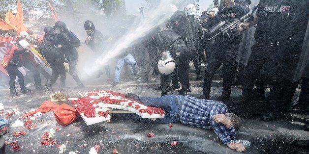 A man lies on the ground as Turkish police use a water cannon to disperse protestors during a May Day rally near Taksim Square in Istanbul on May 1, 2015. Turkish police on used tear gas and water cannon to disperse protesters marking May Day in the Besiktas district of Istanbul as they tried to move towards the Taksim Square protest hub of Istanbul. AFP PHOTO / BULENT KILIC (Photo credit should read BULENT KILIC/AFP/Getty Images)