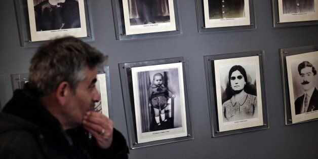 A man looks at pictures in the museum of the victims of Nazism in the small town of Distomo, some 200 kilometers north west of Athens, on March 27, 2015. A small town in central Greece still inhabited today, Distomo has become the symbol of atrocities committed by Nazi troops as they pulled back to Germany in the wake of the Allied Normandy landings in the summer of 1944. On the same day, 650 people including women and children were killed in Ouradour-sur-Glane, a French town that is today twinn