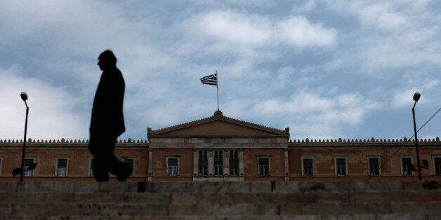 A man walks in front of the Greek Parliament in Athens on November 27, 2012. The eurozone and IMF saved Greece with a re-drawn rescue to avert bankruptcy and to cut the debt mountain on Tuesday which Greek leaders said marked a new beginning for their people facing yet further austerity in the midst of recession. AFP PHOTO / Angelos Tzortzinis (Photo credit should read ANGELOS TZORTZINIS/AFP/Getty Images)