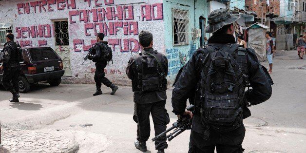BOPE police special forces patrol an alley of the Mare shantytown complex in Rio de Janeiro, Brazil, on May 4, 2015. Rio's police is on the econd phase of replacing the Brazilian army personnel involved in pacification tasks in the 140,000 inhabitants Mare slum complex, in a process they expect to end by June 30. AFP PHOTO / YASUYOSHI CHIBA (Photo credit should read YASUYOSHI CHIBA/AFP/Getty Images)