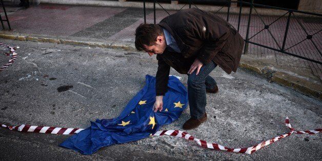 A protester picks up a disgarded European Union flag during a protest rally in Athens on April 23, 2015. European governments have come under increasing pressure to tackle the Mediterranean migrant crisis, with the last shipwreck claiming hundreds of lives on April 19, 2015. AFP PHOTO / LOUISA GOULIAMKI (Photo credit should read LOUISA GOULIAMAKI/AFP/Getty Images)
