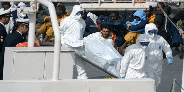 Rescued migrants watch as the body of person who died after a fishing boat carrying migrants capsized off the Libyan coast, is brought ashore along with 23 others retreived by the Italian Coast Guard vessel Bruno Gregoretti at Boiler Wharf, Senglea in Malta on April 20, 2015. More than 700 people are feared dead following the capsize off Libya of a fishing boat that had been crammed with migrants trying to reach Europe. AFP PHOTO / MATTHEW MIRABELLI --- MALTA OUT (Photo credit should read Matthew Mirabelli/AFP/Getty Images)
