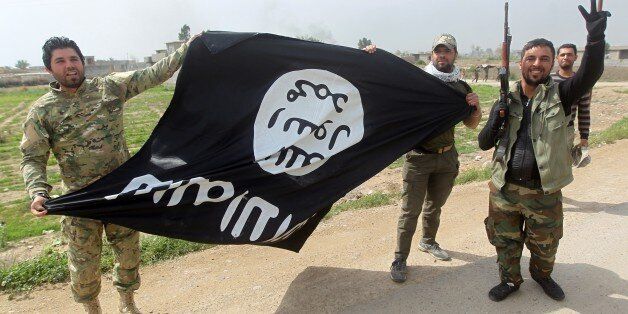 Members of Iraqi paramilitary Popular Mobilisation units, which are dominated by Shiite militias, celebrate with a flag of the Islamic State (IS) group after retaking the village of Albu Ajil, near the city of Tikrit, from the jihadist group, on March 9, 2015. Some 30,000 Iraqi soldiers, police and the increasingly influential paramilitary Popular Mobilisation units, which are dominated by Shiite militias, have been involved in a week-old operation to recapture Tikrit, one of the jihadists' main hubs since they overran large parts of Iraq nine months ago. AFP PHOTO / AHMAD AL-RUBAYE (Photo credit should read AHMAD AL-RUBAYE/AFP/Getty Images)
