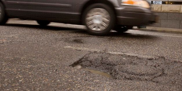 Downtown traffic passes a pothole in Portland, Ore., Thursday, Feb 11, 2010. If you live in Portland and spot a nasty pothole, burned-out streetlight or noxious graffiti, Mayor Sam Adams wants you to grab your iPhone and report it.(AP Photo/Don Ryan)