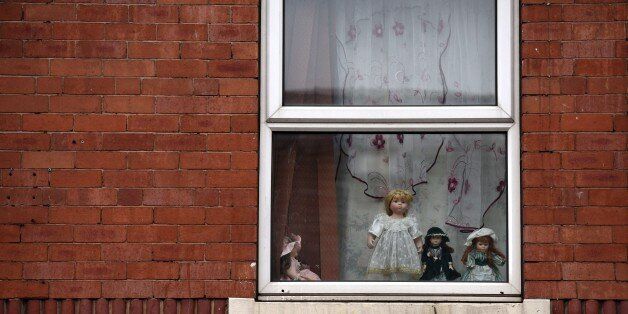 Dolls are displayed in an upper floor window of a house in the Eastwood area of Rotherham, South Yorkshire, North England, on October 6, 2014. An inquiry revealed on August 26, 2014 that some 1,400 minors were sexually abused in the British town of Rotherham over a 16-year period and blamed local authorities for failing to act. The inquiry followed the conviction of five men in 2010 for sexual offences in Rotherham at a trial in which they were found guilty of grooming teenage girls for sex. AFP PHOTO / OLI SCARFF (Photo credit should read OLI SCARFF/AFP/Getty Images)