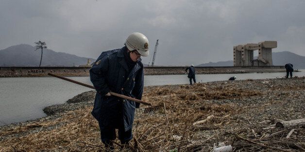 RIKUZENTAKATA, JAPAN - MARCH 11: A police officer searches the shoreline for the remains of tsunami victims or any identifying personal items on March 11, 2015 in Rikuzentakata, Japan. Police from Iwate prefecture continue to search for remains, and personal items that could be returned to loved ones on the 11th of every month. On March 11 Japan commemorates the fourth anniversary of the magnitude 9.0 earthquake and tsunami that claimed more than 18,000 lives, and subsequent nuclear disaster at the Fukushima Daiichi Nuclear Power Plant. (Photo by Chris McGrath/Getty Images)