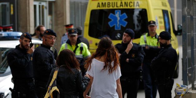 Two young girls walk towards police officers in front of an ambulance, outside a school in Barcelona, Spain, Monday, April 20, 2015. A student walked into a Barcelona school Monday morning and killed a teacher and wounded several other high school students on the 16th anniversary of the massacre of students in shootings at Columbine High School in the U.S. state of Colorado. (AP Photo/Emilio Morenatti)