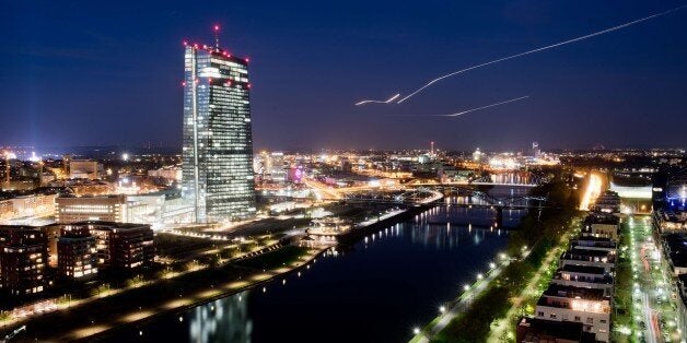 Planes preparing to land at Frankfurt airport draw light lines in the evening sky as at (L) can be seen the illuminated building of the European Central Bank (ECB) in Frankfurt am Main, western Germany, on April 14, 2015. The European Central Bank will be keen to stress on April 15, 2015 that it has no plans to roll back controversial policy measures, as signs multiply that its medicine is beginning to work, analysts said. AFP PHOTO / DPA / BORIS ROESSLER +++ GERMANY OUT (Photo c