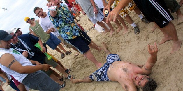 386746 37: Men pour beer on a drunken student on the beach at South Padre Island, Texas March 16, 2001 during the annual rite of Spring Break. Some 125,000 revelers, mostly college students on a break from classes, descend on the Texas beach each year for an alcohol-soaked week of sun, sand and partying. (Photo by Joe Raedle/Newsmakers)