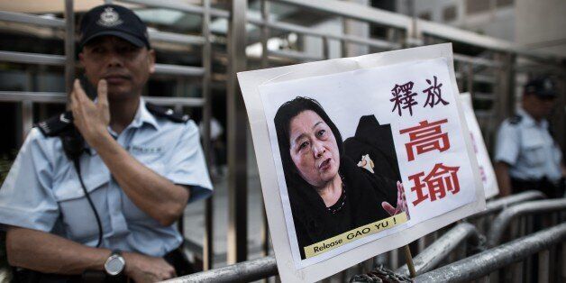 A policeman stands guard outside the China liaison office next to a placard showing a portrait of Chinese journalist Gao Yu left by demonstrators in Hong Kong on April 17, 2015. A Chinese court on April 17, 2015 convicted the 71-year-old journalist of leaking state secrets and jailed her for seven years, it said, in a case seen by rights groups as part of a crackdown on government critics. AFP PHOTO / Philippe Lopez (Photo credit should read PHILIPPE LOPEZ/AFP/Getty Images)