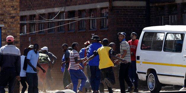 Local residents run away as police fired rubber bullets and teargas to disperse a crowd of anti-immigrant protesters outside a hostel in Actonville, east Johannesburg, South Africa, Thursday, April 16, 2015. Fears of anti-immigrant attacks have escalated sending foreigners seeking refuge in camps and a police station. (AP Photo/Themba Hadebe)