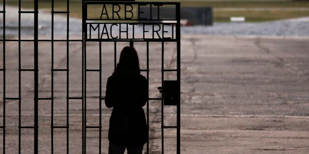 A woman stands in front of the gate of the Sachsenhausen Nazi death camp with the phrase 'Arbeit macht frei' (work sets you free) at the eve of the International Holocaust Remembrance Day, in Oranienburg, about 30 kilometers, (18 miles) north of Berlin, Monday, Jan. 26, 2015. The International Holocaust Remembrance Day marks the liberation of the Auschwitz Nazi death camp on Jan. 27, 1945. (AP Photo/Markus Schreiber)