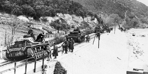 German tanks move along railway tracks on their way to Larissa, Greece, during the occupation of Greece by German forces, May 1941. In the background is the mountain fort