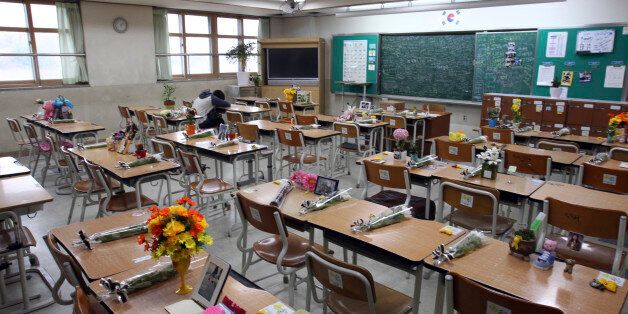 In this April 12, 2015, photo, survivor Yang Jeong-won, a student who was rescued from the sunken Sewol ferry, puts her head on her desk inside a classroom at Danwon High School in Ansan, South Korea, which has become a memorial for her classmates who were killed.