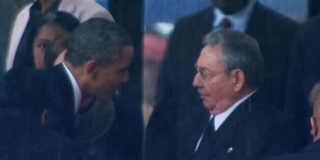 In this image from TV, US President Barack Obama shakes hands with Cuban President Raul Castro at the FNB Stadium in Soweto, South Africa, in the rain for a memorial service for former South African President Nelson Mandela, Tuesday Dec. 10, 2013. The handshake between the leaders of the two Cold War enemies came during a ceremony that's focused on Mandela's legacy of reconciliation. Hundreds of foreign dignitaries and world heads of states gather Tuesday with thousands of South African people t