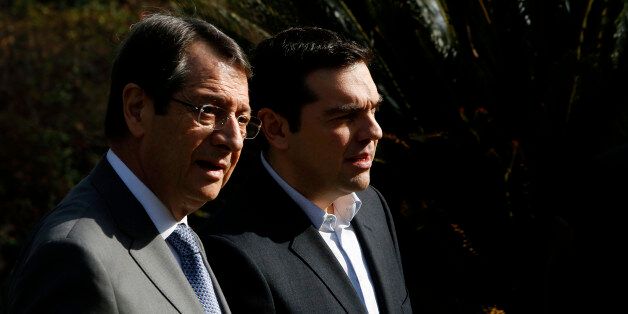 Cyprus' President Nicos Anastasiades, left, and Greek Prime Minister Alexis Tsipras walk at the Presidential Palace following their meeting in the capital Nicosia Monday, Feb. 2, 2015. Tsipras is visiting Cyprus, his first trip abroad as prime minister since his election last month. It's customary for all newly-elected Greek prime ministers to conduct their first trip abroad to Cyprus because of the two countries' deep historic ties. (AP Photo/Petros Karadjias)