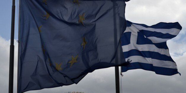 A Greek and an EU flag wave in front of the ancient temple of Parthenon atop the Acropolis hill in Athens on January 13, 2015. Greece could exit the euro by accident, Finance Minister Gikas Hardouvelis said in a new warning of what could happen if anti-austerity leftist party Syriza wins the election later this month. AFP PHOTO / ARIS MESSINIS (Photo credit should read ARIS MESSINIS/AFP/Getty Images)