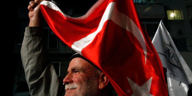 A supporter of the leadership candidate Mustafa Akinci waves a Turkish flag during a rally in the old city of the divided capital of Nicosia at the Turkish Cypriot north part of the island of Cyprus, Tuesday, April 14, 2015. The Turkish Cypriot leadership elections will take place on April 19, 2015. (AP Photo/Petros Karadjias)
