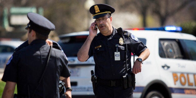 WASHINGTON, DC - APRIL 11:A U.S. Capitol Police officer talks on his phone near the west front of the U.S. Capitol on Capitol Hill, April 11, 2015 in Washington, DC. According to the U.S. Capitol Police, the Capitol was on lockdown after shots were fired and a suspicious package was investigated. According to the U.S. Capitol Police, a person suffered a self-inflicted gunshot wound. (Photo by Drew Angerer/Getty Images)