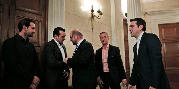 Greek Prime Minister Alexis Tsipras, right, looks on as European Parliament President Martin Schulz, center, shakes hands and talks with Greek Minister of State Nikos Pappas, second left, following a news conference after their meeting at Maximos Mansion in Athens, Thursday, Jan. 29, 2015. Schulz is the first European Union official to meet Tsipras, whose new Cabinet alarmed the Greek stock market Wednesday with promises to renege on a series of key budget commitments made by previous administra