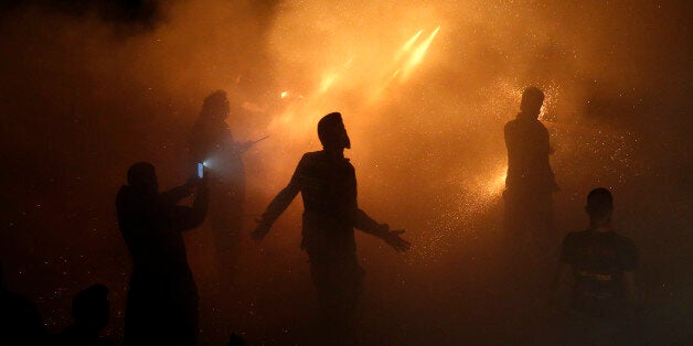 Men ignite rockets during Greek Orthodox Easter celebrations on the eastern Aegean island of Chios, Greece, late Saturday, April 11, 2015. Thousands of handmade rockets are fired every year on Great Saturday night, before the Resurrection, by locals of the two rival churches of Agios Markos and Panagia Erithiani, in the village of Vrontados. (AP Photo/Petros Giannakouris)