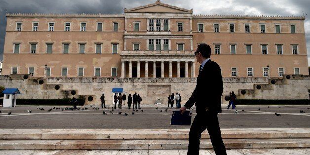 A woman walks in front of the Greek Parliament in Athens on April 7, 2015. Greek lawmakers voted on April 7 to set up a committee to examine the circumstances under which Greece agreed to bailouts totaling 240 billion euros (USD 260 billion) with the European Union and International Monetary Fund. AFP PHOTO / ARIS MESSINIS (Photo credit should read ARIS MESSINIS/AFP/Getty Images)
