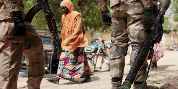 In this photo taken Wednesday, April 8, 2015, a woman walks past Nigerian Soldiers at a checkpoint in Gwoza, Nigeria, a town newly liberated from Boko Haram. Each day brings new reports of atrocities, with mass graves being discovered in towns seized back from the militants who had set up a so-called âIslamic caliphateâ across a great swath of northeast Nigeria. Boko Haram's nearly 6-year-old Islamic uprising in northeast Nigeria that has killed thousands â a reported 10,000 just last year â and forced more than 1.5 million from their homes. (AP Photo/Lekan Oyekanmi)