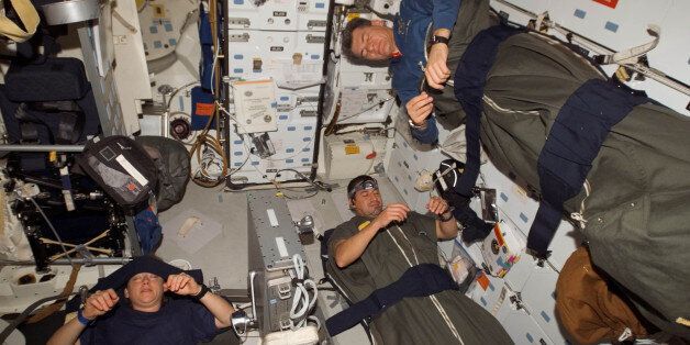 In this image provided by NASA, astronauts Pam Melroy, George Zamka, bottom right,and European Space Agency's Paolo Nespoli, sleep in their sleeping bags, which are secured on the middeck of the Space Shuttle Discovery while docked with the International Space Station, Thursday, Nov. 1, 2007. (AP Photo/NASA)