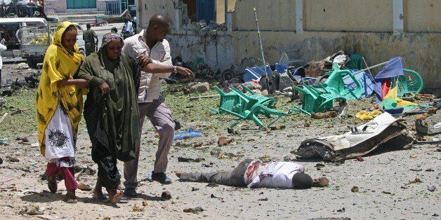 A wounded woman is helped at the scene of a car bomb outside the Education Ministry in Mogadishu on April 14, 2015. Somalia's Al-Qaeda-linked Shebab militants on April 14 blasted their way into the higher education ministry with a car bomb before storming the building and killing six people. Police and witnesses said the car bomb caused a huge explosion to force their way into the fortified building, before gunmen entered with heavy gunfire. AFP PHOTO / MOHAMMED ABDIWAHAB (Photo credit should read Mohamed Abdiwahab/AFP/Getty Images)