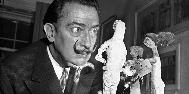** FILE ** Resting his chin on the handle of his cane, Spanish surrealist painter Salvador Dali studies an exhibit of contemporary Greek art in New York, Jan. 4, 1956. Dali called his trademark mustache his