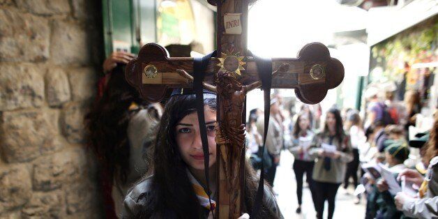 A Palestinian Catholic worshiper holds a cross during the Good Friday procession along the Via Dolorosa...