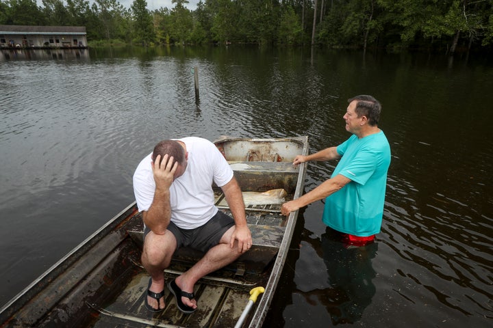 Stephen Gilbert, left, and his father-in-law sit in front of their flooded property on Friday, Sept. 20, 2019, in the Maurice
