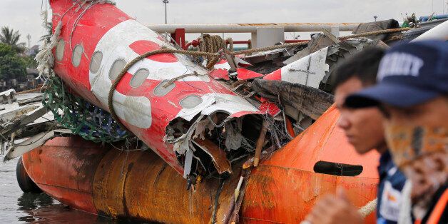 Security guards stand near the newly-recovered remains of the fuselage of the ill-fated AirAsia Flight 8501 on the deck of rescue ship Crest Onyx at Tanjung Priok port in Jakarta, Indonesia, Monday, March 2, 2015. The Airbus A320-200 with 162 people on board crashed into the Java Sea on Dec. 28, 2014 while flying from Surabaya, East Java, to Singapore. (AP Photo/Dita Alangkara)