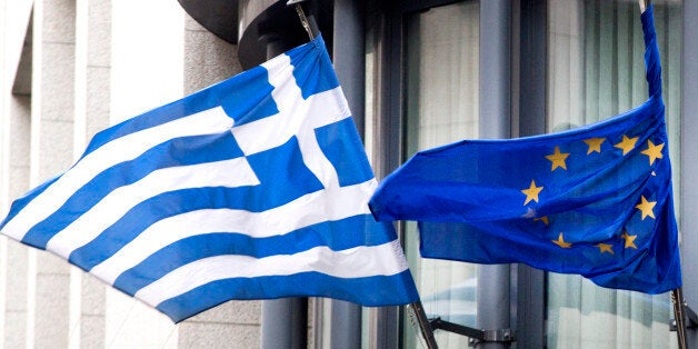 The Greek, left, and EU flag flap in the wind outside the Greek embassy in Brussels on Friday, Feb. 20, 2015. Eurozone finance ministers meet for a crucial day of talks to see whether a Greek debt relief proposal is acceptable to Germany and other nations using the common currency. (AP Photo/Virginia Mayo)