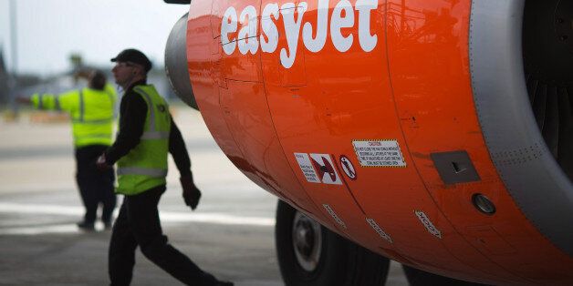 An EasyJet logo sits on the orange cowling of an aircraft engine as a members of the ground crew work at a departure gate at the north terminal of London Gatwick airport in Crawley, U.K., on Thursday, Nov. 6, 2014. EasyJet has established a footprint at locations such as Amsterdam Schiphol, where it announced plans to base planes in July, and is ramping up operations at London Gatwick airport, its biggest single base. Photographer: Simon Dawson/Bloomberg via Getty Images