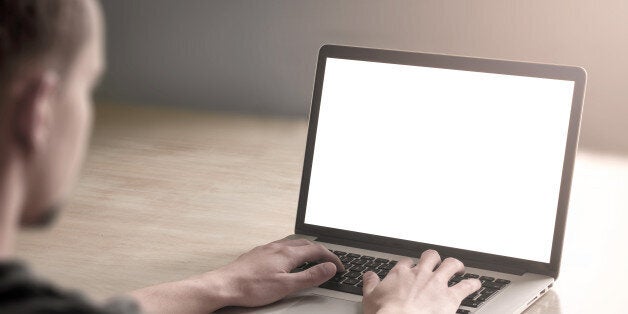 Man working on his laptop computer with blank screen.