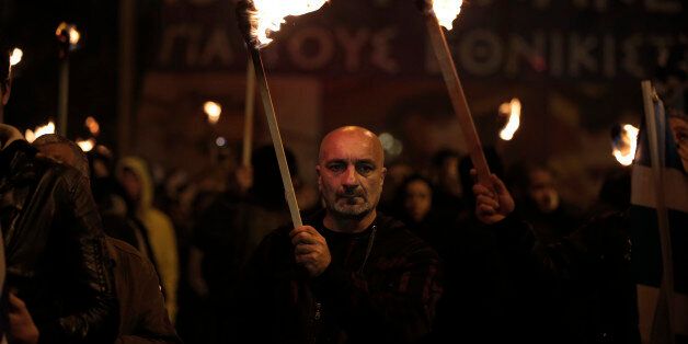 Supporters of Greece's extreme right party Golden Dawn, hold torches during a rally to commemorate a 1996 incident which cost the lives of three Greek navy officers and brought Greece and Turkey to the brink of war, in central Athens, Saturday, Jan. 31, 2015. The extreme right, anti-immigrant Golden Dawn party, which has Nazi roots, received the third-place in Sunday, Jan. 25's election. Its showing comes despite the fact that the party's leader and most of its lawmakers are behind bars, facing