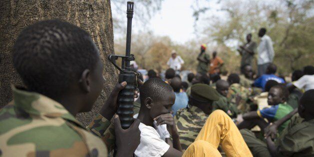 Young boys, children soldiers sit on February 10, 2015 with their rifles at a ceremony of the child soldiers disarmament, demobilisation and reintegration in Pibor oversawn by UNICEF and partners. UNICEF and its partners have overseen the release of another 300 children from the Cobra Faction armed group of former rebels of David Yau Yau. The children in Pibor, Jonglei State, surrendered their weapons and uniforms in a ceremony overseen by the South Sudan National Disarmament, Demobilization and