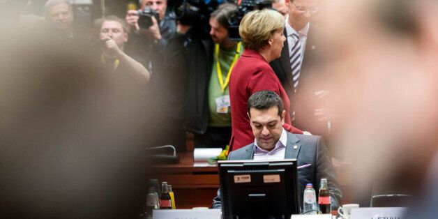 German Chancellor Angela Merkel, center rear, walks by Greek Prime Minister Alexis Tsipras during a round table meeting at an EU summit in Brussels on Thursday, March 19, 2015. Tensions over Greece's massive financial bailout overshadowed a European Union summit amid fears that the country could accidentally drop out of the euro, triggering a crisis across the currency zone shared by 19 nations. (AP Photo/Geert Vanden Wijngaert)