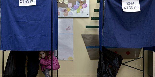 A girl looks out a voting booth at a polling station in Athens on January, 2015. Greece votes today in a crucial general election that could bring the anti-austerity Syriza party to power and lead to a re-negotiation of the country's international bailout. AFP PHOTO / ARIS MESSINIS (Photo credit should read ARIS MESSINIS/AFP/Getty Images)