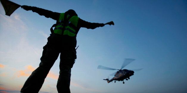 A member of the Danish military personnel gives the signal to a Danish air force helicopter to leave from the Danish war ship